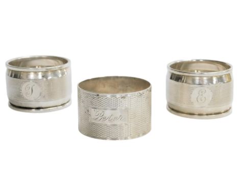 A pair of George V silver napkin rings, with engine turned decoration, circular reserve, initial engraved, Birmingham 1929, a
