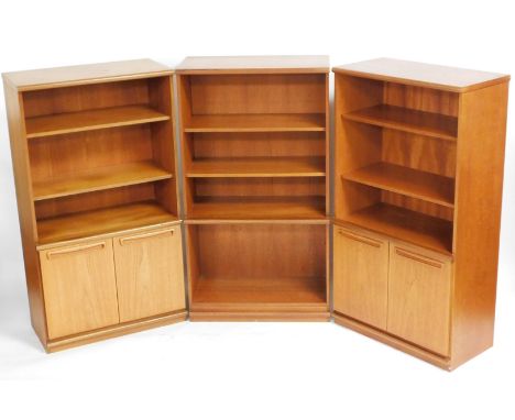 Three mid century teak lounge units, comprising a four shelf bookcase, and a pair of two shelf cupboard bookcases, all raised
