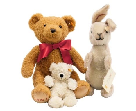 A Steiff gold brown Cosy Teddy Bear 2023, two Winnie the Pooh Rabbits number 02025, and a small white Teddy, 17.5cm high. (3)