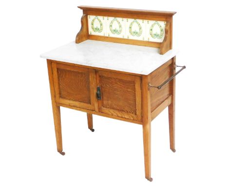 A Victorian oak and marble top wash stand, with a four tile splash back, above a pair of cupboard doors, raised on tapering s