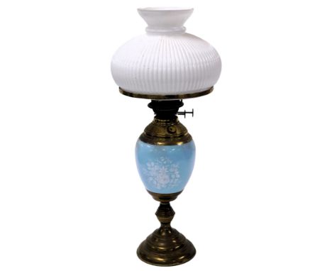 An early 20thC duplex brass and pottery oil lamp, a central blue reservoir, decorated in white slip with flowers, with a whit