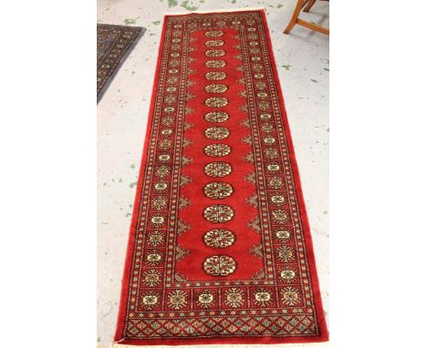 Pakistan Bokhara runner with a single row of gols on a red ground, 2.39 x 81cms together with a similar rug with two rows of 