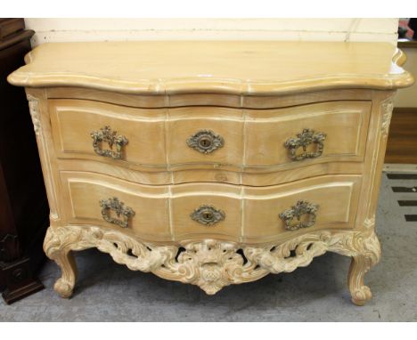 Reproduction limed pine serpentine fronted commode chest of two long drawers, above a carved frieze and cabriole supports, wi