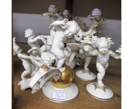 Pair of 20th Century German porcelain twin light candelabra in the form of kneeling putti, together with a garniture of three