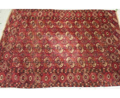 Tekke rug with four rows of nine gols on a wine ground with borders, 172cms x 125cms approximately (at fault), together with 