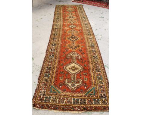 Hamadan runner with central four medallion design, and multiple borders on a red brick ground (some moth damage) 415cms x 107