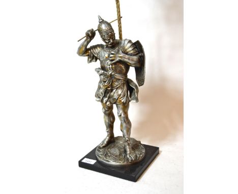 Silvered metal table lamp in the form of a classical warrior with sword and shield, mounted on a black slate plinth and adapt