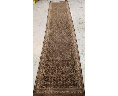 Indo Persian runner with an all-over Herati design on a dark ground with narrow borders, 380cms x 74cms approximately 