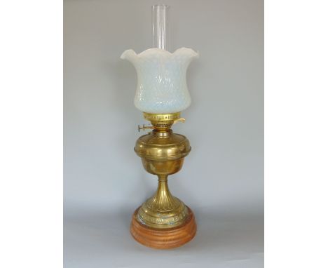 A late 19th century French brass oil lamp, with brass reservoir and tapered fluted column, upon a turned oak stand, the lamp 