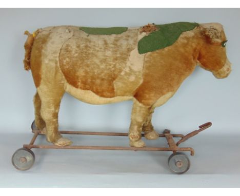 An old child's straw filled pull along toy bull/cow raised on an iron framework (possibly Steiff) (AF) 