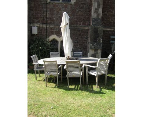 A weathered contemporary teak Cotswold Collection drawleaf garden table with D shaped ends and single additional bi-fold leaf