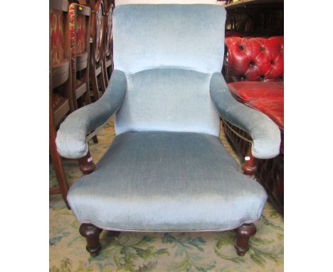 A Victorian armchair with light blue ground upholstered seat, scrolled back and arms and raised on turned supports