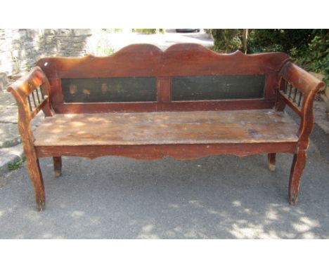 A European red stained pine bench/low settle with shaped outline, panelled back, solid seat and open stick panelled arms, 6ft