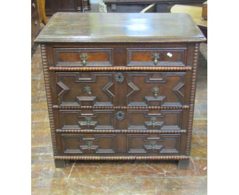 A small 18th century oak chest of four long drawers with applied geometric mouldings, additional split spindle bobbin shaped 