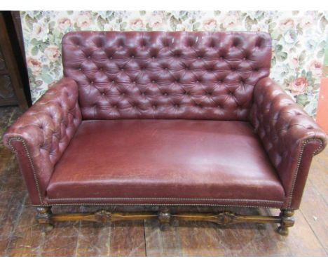 An Edwardian button back two seat sofa upholstered in brown leather raised on a turned showwood frame 130 cm wide