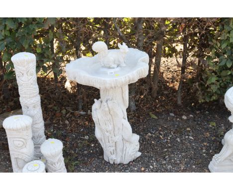 A cast concrete garden bird bath in the form of a tree trunk surrounded by squirrels and foliage with squirrel motif to top o