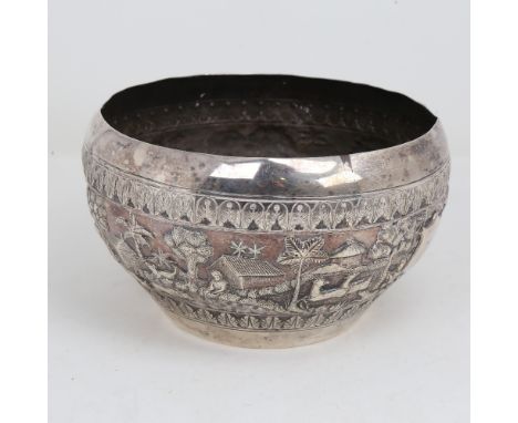 An early 20th century large Burmese silver rice bowl, relief embossed lion hunting and village scenes, peacock and snake make