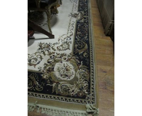 A WOOL RUG the beige, light brown and dark blue ground with central floral panel within a conforming border 295cm x 200cm