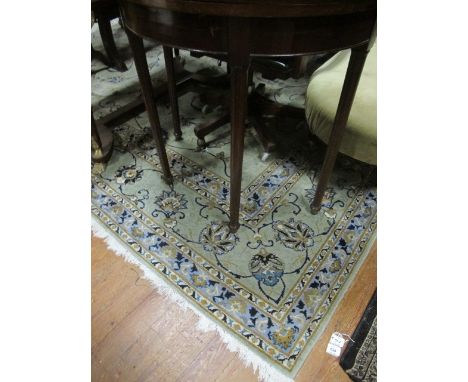 A WOOL RUG the light green and light blue ground central floral panel within a conforming border 400cm x 308cm