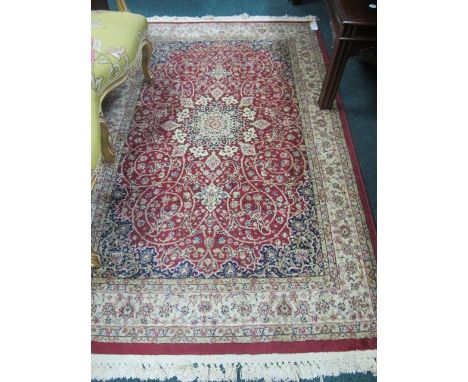 A WOOL RUG the wine and beige ground with central floral panel within a conforming border 190cm x 115cm