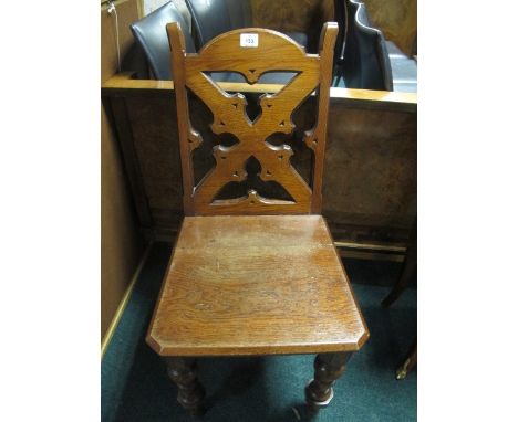 AN OAK GOTHIC STYLE HALL CHAIR with pierced Gothic tracery back and panel seat on turned legs