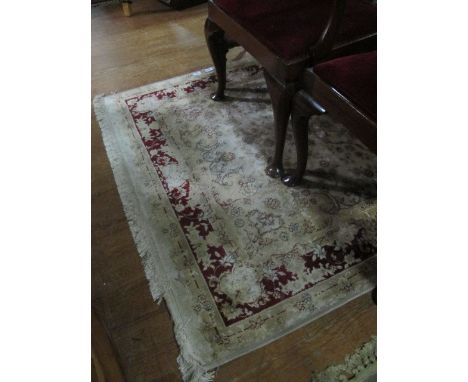 A WOOL RUG the beige ground with central floral panel within a wine floral border 203cm x 134cm