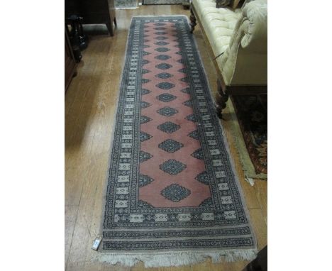 A BOOKHARA WOOL RUNNER the pink central panel with palmets within a conforming border 302cm long