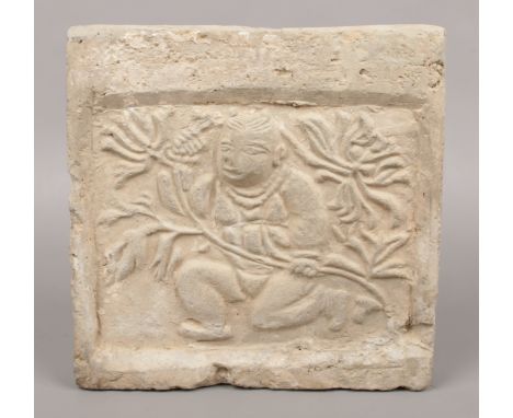 An Oriental carved stone square panel. Decorated in relief with a crouching figure collecting flowers, 27cm square. 