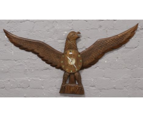 A carved hardwood eagle wall clock with quartz movement. 