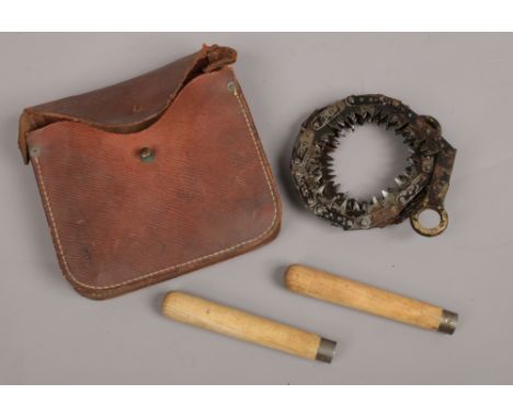 A WWII leather cased military issue chain saw with two detachable handles, broad arrow mark to the leather case 1943. 