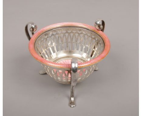 An early 20th century white metal openwork basket. With three double scrolling handles terminating on paw feet and ornamented