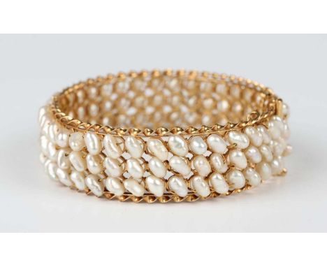 A gold and freshwater cultured pearl oval hinged bangle, mounted with three rows of freshwater cultured pearls, on a sliding 