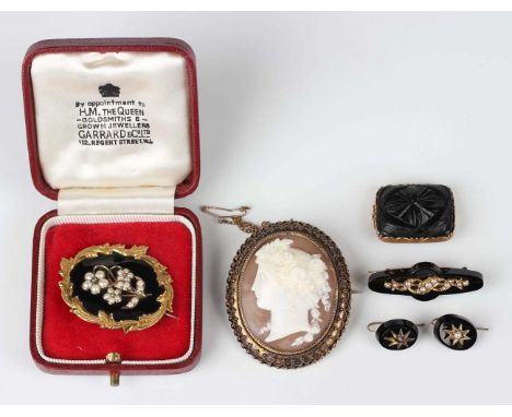 An early Victorian black enamelled shaped oval mourning brooch, the front mounted with half-pearls and a colourless gem in a 