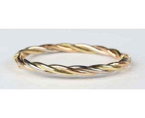 A three colour gold oval hinged bangle in a ropetwist design, on a sprung clasp, detailed ‘750’, weight 13.7g, inside width 5