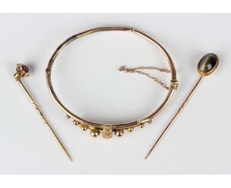 A gold oval hinged bangle, the front with beaded decoration, detailed ‘9ct’, weight 6.7g (broken), a quartz cat’s eye stickpi