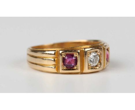 A late Victorian 18ct gold, ruby and diamond ring, mounted with a circular cut diamond between two cushion cut rubies in squa