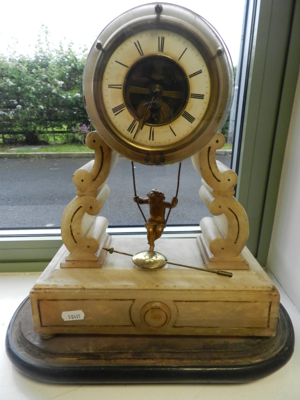 A French mantle clock with swinging cherub pendulum