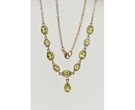A YELLOW METAL PERIDOT NECKLACE, designed as a row of nine oval cut peridots, each in a claw setting, suspending a pear cut p