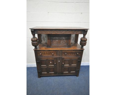 A 20TH CENTURY OAK COURT CUPBOARD, the top with a single cupboard door, scrolled and foliate carved detail, bulbous supports,