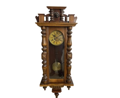 A late 19th century German spring driven wall clock in a mahogany case with a fully glazed door, case with applied carvings a