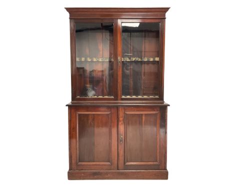 Mahogany gun cabinet , the projecting cornice over two glazed doors, opening to reveal fifteen gun holders, over two cupboard