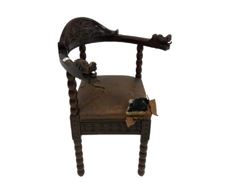 Oak corner chair with blind carved back rail over leather seat, raised on turned bobbin supports 