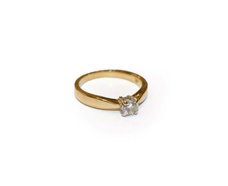 A diamond solitaire ring, the round brilliant cut diamond in a white four claw setting, to a yellow tapered shoulder plain po