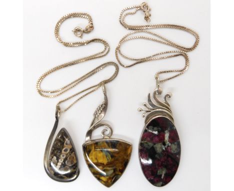 Three American designer pendants by Tom Burns, of Vermont, set with blue and gold tiger's eye, fossilized shells, and ruby in
