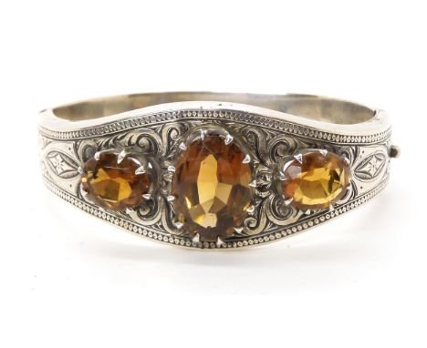 A white metal bangle set with citrines, with hand engraved decoration Condition Report:One citrine has significant chips, a f
