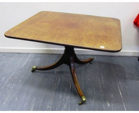 A GEORGIAN MAHOGANY RECTANGULAR TILT-TOP BREAKFAST TABLE the turned pedestal on outswept tripod supports with brass caps and 