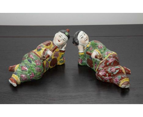 Pair of polychrome porcelain figures smoking opium Chineseeach modelled recumbent, smiling and holding an opium pipe, 17cm an