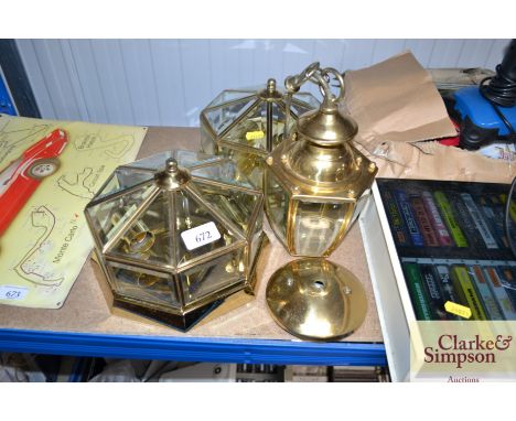 A pair of brass and glass wall lights together with a similar hanging light fitting