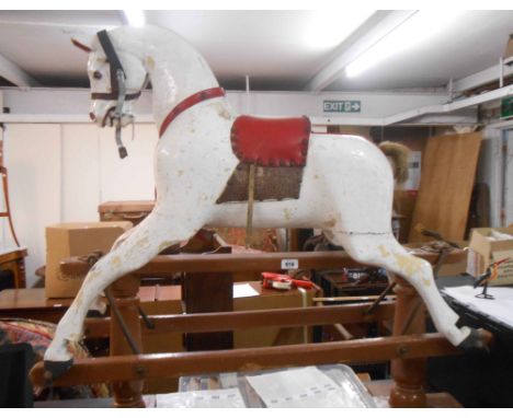 An early 20th Century carved wood rocking horse, set on pillar base with later painted finish and upholstered saddle