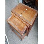 A small nest of three tables with carved detailing